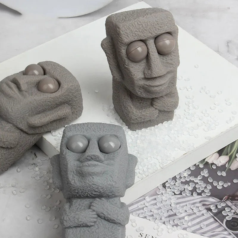 Stone man releases stress toy slowly rebounds soft Moai statue squeeze eyes interested expression relaxes stress children's gift